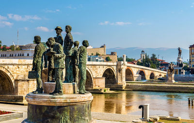 Statue of bridge over water against sky