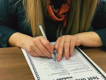 Midsection of woman reading book on table