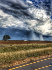 Scenic view of field against storm clouds