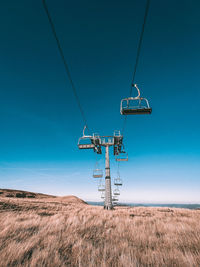 Ski lift on field against clear blue sky