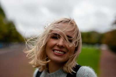 Close-up portrait of cheerful beautiful woman against sky