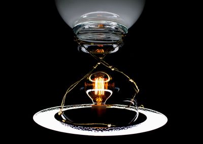 Close-up of illuminated lamp over black background