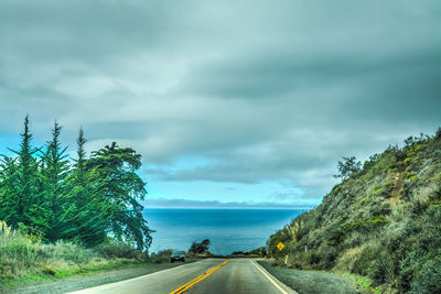 Road by trees against sky