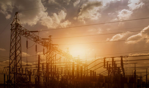 Low angle view of electricity pylon against cloudy sky