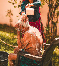 Daughter bathing her old mother in yard