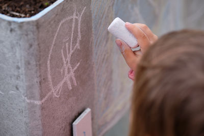 Close-up of woman holding paper against wall