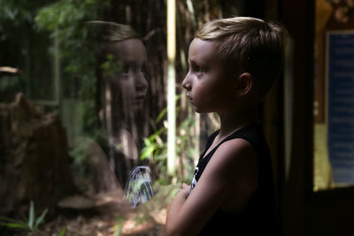 Boy looking at his reflection in glass