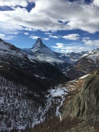 Scenic view of snow covered mountains against cloudy sky