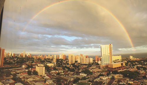 Aerial view of rainbow over buildings in city against sky