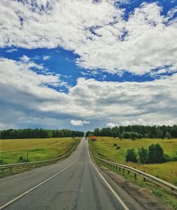 Empty road amidst field against sky