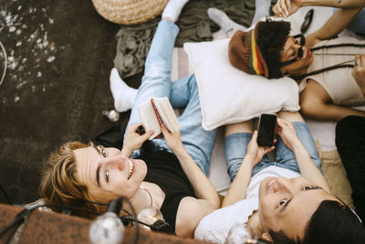 High angle view of male friends sitting by woman lying down