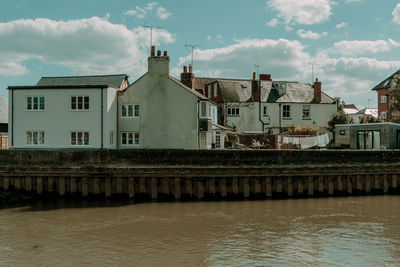 Buildings by river against sky