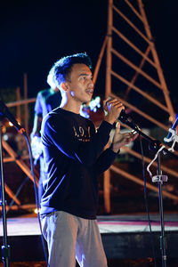 Young man with arms outstretched at night