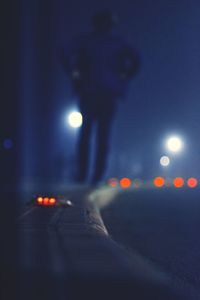 Rear view full length of man walking on sidewalk at night