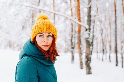 Portrait of young woman standing against trees