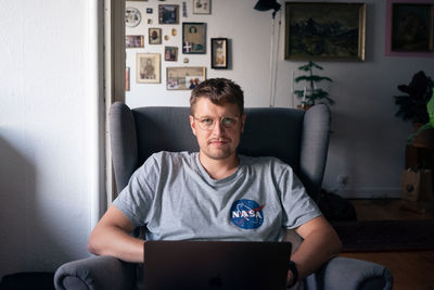 Portrait of young man sitting on sofa at home