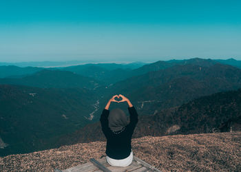 Rear view of woman standing on mountain against sky