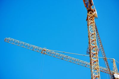 Low angle view of crane against clear blue sky