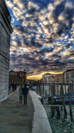 Man standing on bridge in city against sky at night