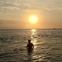 Silhouette man in swimming pool against sea during sunset