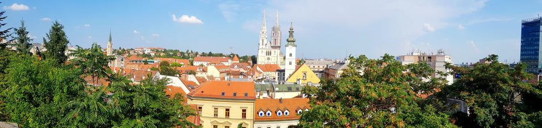 Panoramic view of trees and buildings against sky