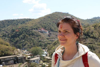 Portrait of young woman standing against mountain