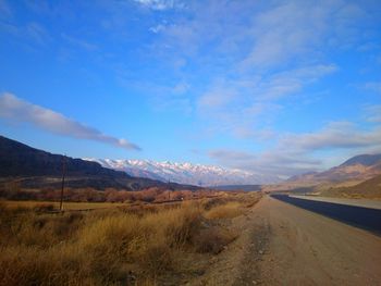 Country road along landscape against blue sky