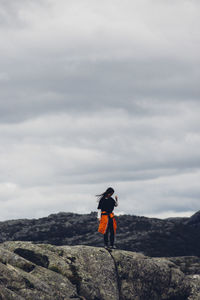 Man standing on rock against sky