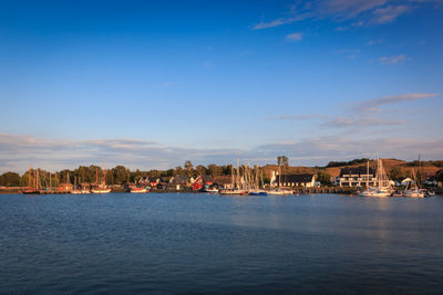 Buildings by sea against blue sky