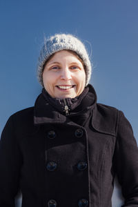 Portrait of smiling woman standing against clear blue sky