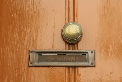 Close-up of mail slot on wooden door