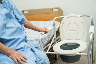 Flush toilet and shower chair in bathroom for old elder people.