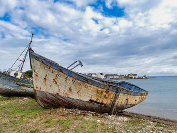 Abandoned ship on beach against sky