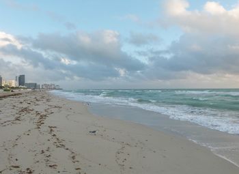 Scenic view of beach against cloudy sky