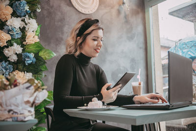 Young woman using mobile phone while sitting on table