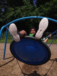 Portrait of boy sitting on play equipment at park