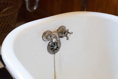 Close-up of faucet on free standing bathtub in bathroom