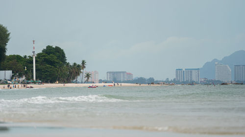 Sea and buildings in city against sky