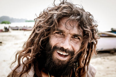 Close-up portrait of smiling mid adult man against sky