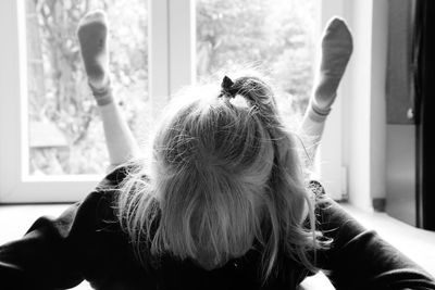 Rear view of woman looking at window at home