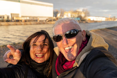 Middle aged couple wearing winter clothes taking a selfie on the river banks - people in recreation