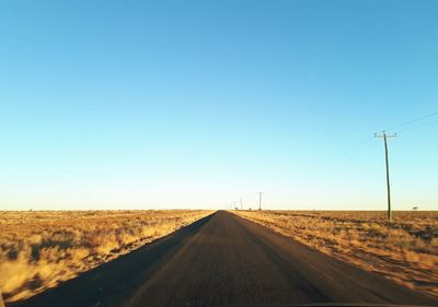 Road amidst land against clear sky