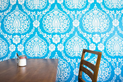 Table and chair by patterned wall