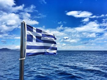 Greek flag at beach against sky