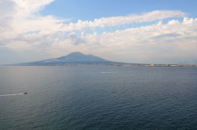 Distant view of mount vesuvius seen from sea against sky