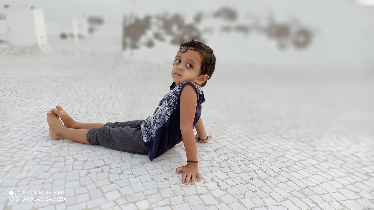 SIDE VIEW OF WOMAN LOOKING AWAY WHILE SITTING ON FLOOR