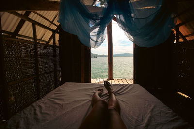 Woman watching a view of the sea from inside a bungalow