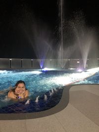 Portrait of young woman in swimming pool at night