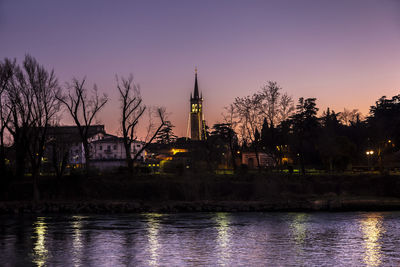 River by buildings against sky at dusk