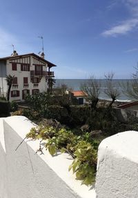 Houses by sea against buildings in city against sky